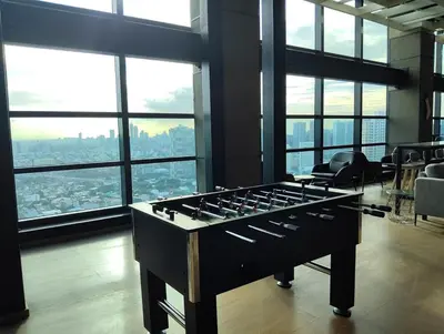 a large foosball table in a room with windows at Elements Residences 1br fully furnished with balcony in Manila