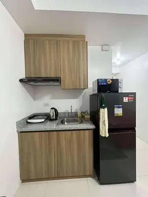 a kitchen with a sink and a black refrigerator at Elements Residences 1br fully furnished with balcony in Manila