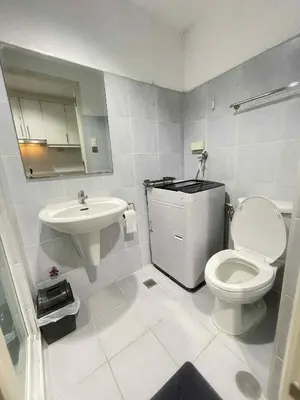 a white bathroom with a toilet and a sink at Woodox Condotel in Manila