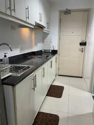 a kitchen with white cabinets and a door with a sink at Woodox Condotel in Manila