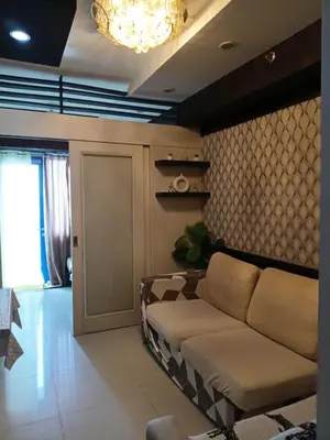 a living room with a couch and a chandelier at Sea Residences Serenity in Manila