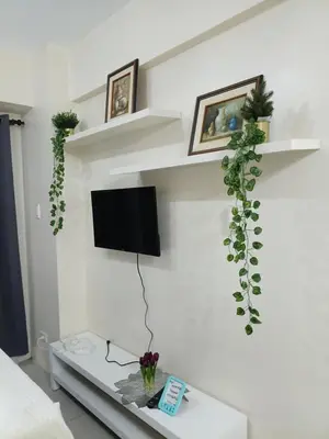 a living room with a tv on a white wall at Sea Residences Serenity in Manila