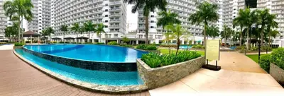 a swimming pool in front of a large building at Ben's stay cation in Manila