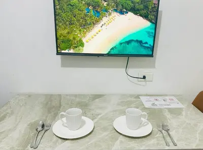 two cups and spoons on a table with a flat screen tv at Rooms near Aiport - Credit Card accepted 0995 - 448 - 8872 in Manila