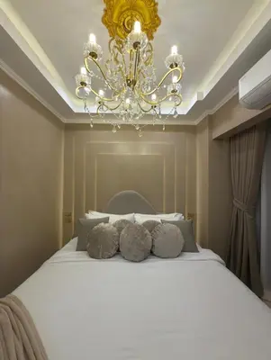a bedroom with a large white bed with a chandelier at Pure Elegance 1BR Suite in Manila