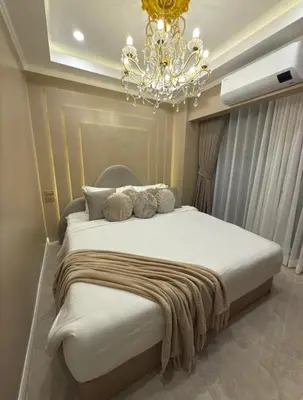 a bedroom with a large white bed with a chandelier at Pure Elegance 1BR Suite in Manila