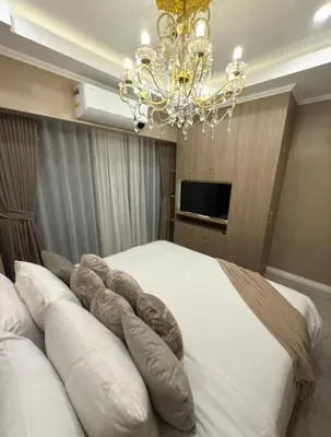 a bedroom with a large bed with a chandelier at Pure Elegance 1BR Suite in Manila