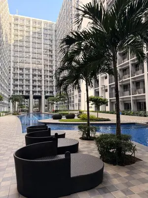 a courtyard with chairs and palm trees in a building at Modern Staycation near MOA & NAIA with PS4, Netflix, Wi-Fi in Manila