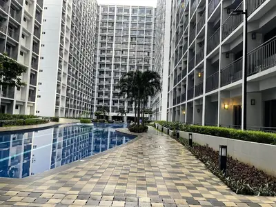 a walkway between two tall buildings with a swimming pool at Cozy Haven Staycation in Manila