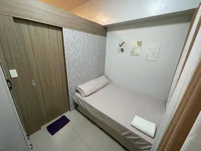 a small bed in a small room with a door at Cozy Haven Staycation in Manila