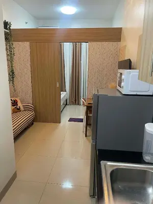 a kitchen with a sink and a living room at Cozy Haven Staycation in Manila