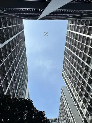 an airplane is flying between two tall buildings at Cozy Haven Staycation in Manila