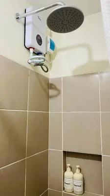 a shower with a hair dryer and two bottles on a wall at Chill Escape Prisma near BGC and Ortigas in Manila