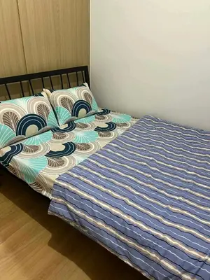 a bed with a blue and white blanket on it at Transient Home by Molave in Manila
