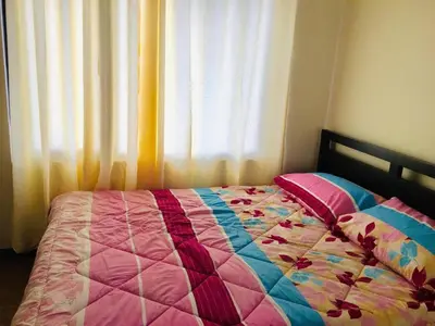 a bed with a quilt on it in front of a window at Paseo Verde in Manila