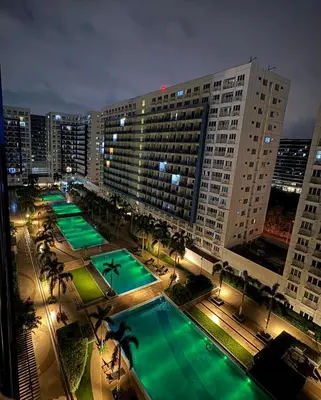 a large building with a pool in front of it at night at J&K Staycation in Manila