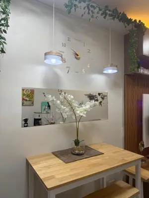 a clock on a wall with a vase of flowers on a table at Shore Bliss Staycation by Aims in Manila