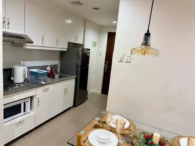 a kitchen with white cabinets and a table with plates at Affordable, Cozy & Quiet 1BR in BGC - Ideal for Short & Long Stays in Manila