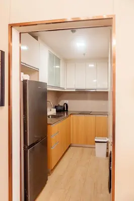 a kitchen with a stainless steel refrigerator and wooden cabinets at Premium Condo units at Gentry Manor beside Okada Manila and near Airport in Manila