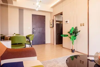 a living room with a table and green chairs at Premium Condo units at Gentry Manor beside Okada Manila and near Airport in Manila