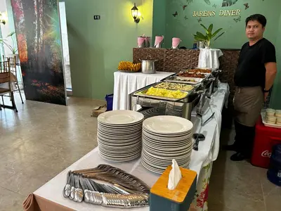 a man standing next to a table with plates of food at Jarens Diner in Silang