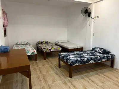 a room with three beds and a table at Jarens Diner in Silang