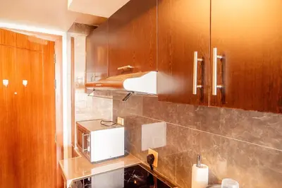 a kitchen with wooden cabinets and a microwave at Elegant Condo at ETON Baypark Manila in Manila