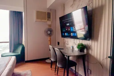 a living room with a table and a television on a wall at Elegant Condo at ETON Baypark Manila in Manila