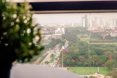 a view of a city from a window with a flag at Elegant Condo at ETON Baypark Manila in Manila