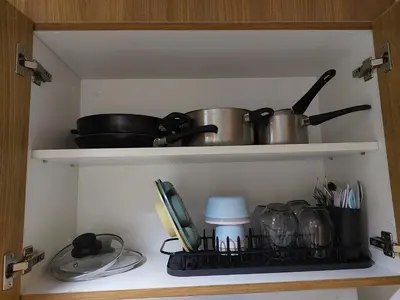 a kitchen shelf with pots and pans and utensils at Shore Residence 3 Mall of Asia by Balai Selah in Manila