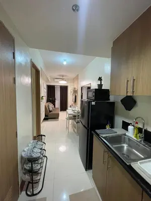 a kitchen with a sink and a black refrigerator at Shore Residence 3 Mall of Asia by Balai Selah in Manila