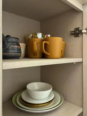 a shelf with plates and cups and bowls on it at Stylish & Serene Penthouse in Manila