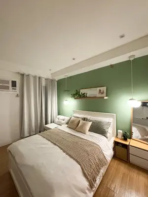 a bedroom with a white bed with a green wall at Top-Floor Studio in Makati with City Views Good For 2-3 Pax in Manila