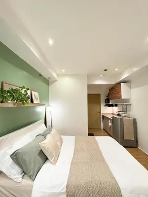 a bedroom with a white bed and a kitchen at Top-Floor Studio in Makati with City Views Good For 2-3 Pax in Manila
