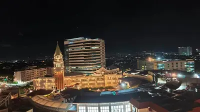 a city skyline at night with a clock tower at Venice Condotel in Manila