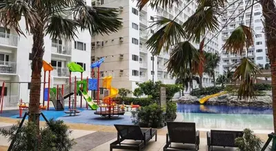 a playground with a slide in a building with palm trees at Shore Residences in Pasay Manila, near Mall of Asia and Manila Airport in Manila