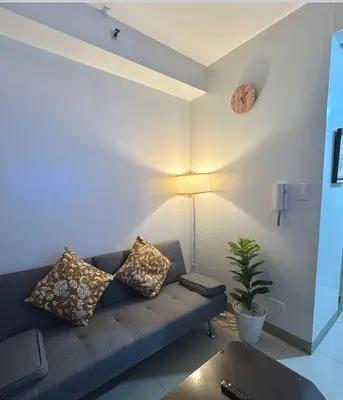 a living room with a couch and a clock on the wall at Mall of Asia Staycation, located in Shore Residences Pasay Manila near Manila Airport in Manila