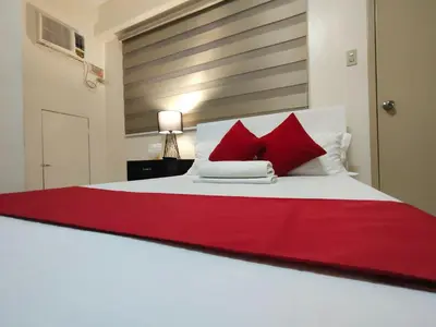 a bedroom with a white bed with red pillows at Orangenest Apartelle in Sampong