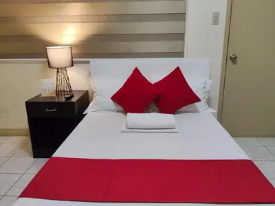 a bedroom with a white bed with red pillows at Orangenest Apartelle in Sampong