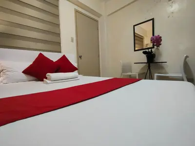 a bedroom with a large white bed with red pillows at Orangenest Apartelle in Sampong