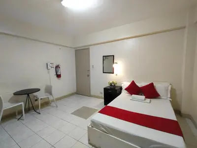 a bedroom with a bed and a table and a phone at Orangenest Apartelle in Sampong