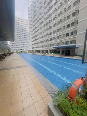 a large swimming pool in a building with tall buildings at Ellain's Cozy Staycation-SMDC Green 2 Residences in Dasmariñas