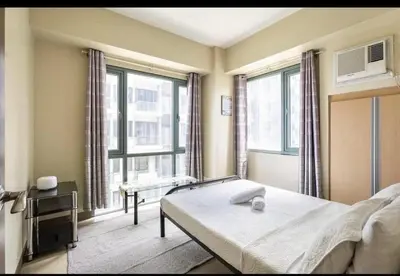 a bedroom with a bed and a large window at 1 Bedroom Apartment Condo Across Manila Airport NAIA T3 in Manila