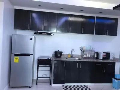 a kitchen with black cabinets and a white refrigerator at Manila Skyview suite at Birch tower condo in Manila