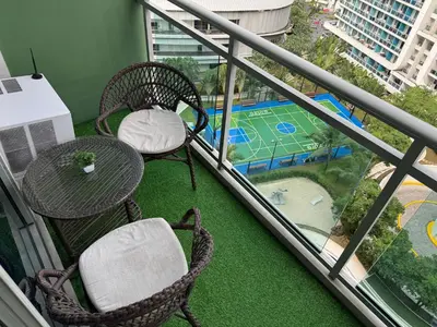 a balcony with two chairs and a table and a playground at Casa Est Staycation - Azure Urban Resort Residences in Manila