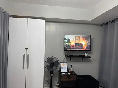 a living room with a fan and a tv on the wall at Casa Est Staycation - Azure Urban Resort Residences in Manila