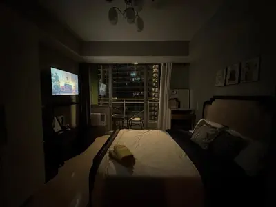 a bedroom with a bed and a window with a television at Casa Est Staycation - Azure Urban Resort Residences in Manila