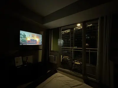 a dark room with a tv and a bed and a window at Casa Est Staycation - Azure Urban Resort Residences in Manila