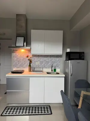 a kitchen with white cabinets and a refrigerator at Casa Est Staycation - Azure Urban Resort Residences in Manila