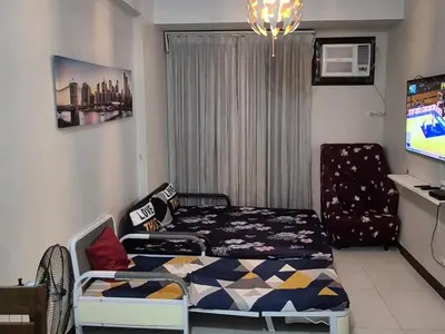 a bedroom with a bed and a chair and a television at A&G Condotel Right Across NAIA Terminal 3 in Manila